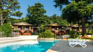 A pool area with lounge chairs, a clear blue pool, and two buildings with balconies. - Holiday Home in Manerba del Garda Near Lake (Manerba del Garda)
