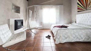Un dormitorio con una cama, una silla blanca, un televisor y un elemento decorativo en la pared.