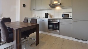 A modern kitchen with a dining area, stainless steel appliances, and light-colored cabinetry. - Ferienhaus mit Sauna in Boiensdorf am Salzhaff (Boiensdorf)
