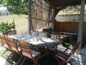 Une terrasse extérieure avec une table ronde et des chaises, un barbecue et une clôture en bambou.