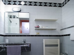 A bathroom with a mirror, a sink, a towel, a heater, and a shelf with toiletries. - Belvilla by OYO Catalani Bilo (Riccione)