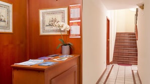 A reception desk with a potted orchid, framed artwork, and a directory sign. - Belvilla by OYO Catalani Bilo (Riccione)