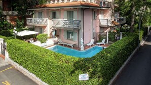 A multi-story building with a swimming pool surrounded by greenery. - Belvilla by OYO Catalani Bilo (Riccione)