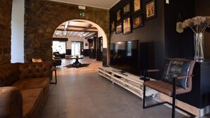 Un hall d’entrée avec un mur en pierre, un banc en bois, un canapé et un téléviseur à écran plat.