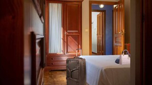 A hotel room with a bed, a suitcase, a wardrobe, and a mirror. - Rural house Pontevedra. Pool, garden and barbecue (Vilaboa)