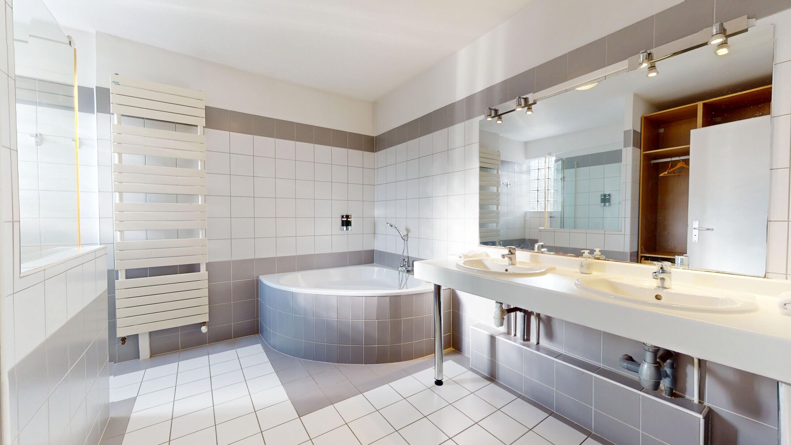 Ein modernes Badezimmer mit einer freistehenden Badewanne, zwei Waschbecken und einem großen Spiegel.