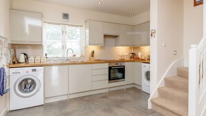 Une cuisine moderne dotée d’appareils électroménagers intégrés, d’un lave-linge et d’un escalier menant à un autre niveau.