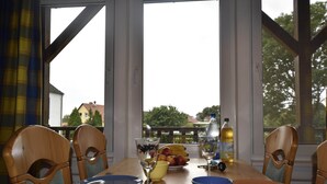Ein Esstisch mit Stühlen, Tellern, Schüsseln, einem Weinglas und einer Flasche Olivenöl.