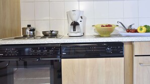 Eine Küche mit einer Kaffeemaschine, einem Sieb voller Gemüse und einem Herd.