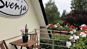 En utomhusplats med sittmöbler, ett bord och stolar, en krukväxt och ett räcke med blomlådor.