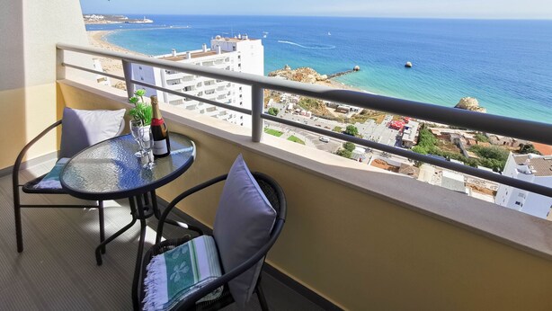 A balcony with a table, chairs, and a bottle of champagne. - Flat Rose Garden Sea View (Portimão)