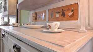 A kitchen counter with a white cup and saucer, a white plate, and a wooden cabinet.