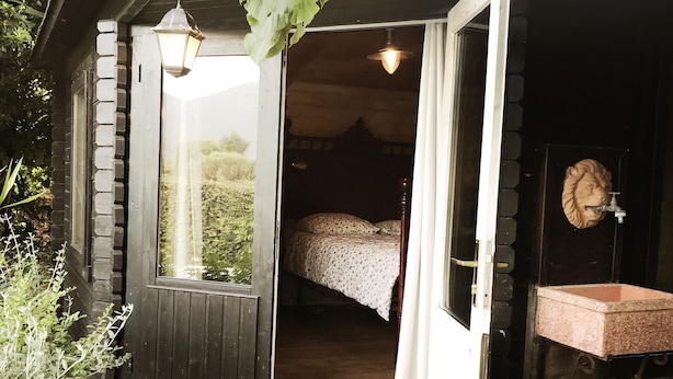 A wooden cabin with a bed, a sink, and a window.