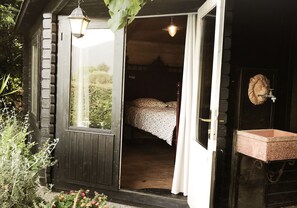 A wooden cabin with a bed, a sink, and a window.