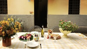An outdoor dining table set with flowers, plates, and glasses, with a building in the background.