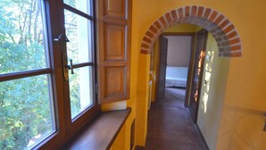 A hallway with a wooden door, a window, and an arched brick feature.