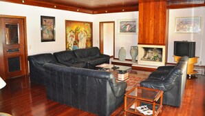 A living room with a sectional sofa, a coffee table, a fireplace, and artwork on the walls. - Villa in Vilamoura With Private Pool & BBQ (Loulé)