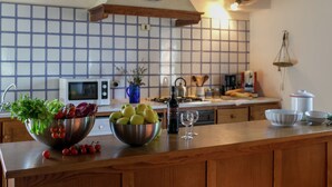 Cocina con encimera de madera, microondas y salpicadero de azulejos.