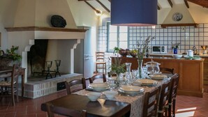 Un comedor con una mesa preparada para cuatro, una chimenea y una cocina al fondo.