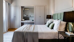 Un dormitorio con una cama grande, una mesita de noche con lámpara, un aparador y un espejo.