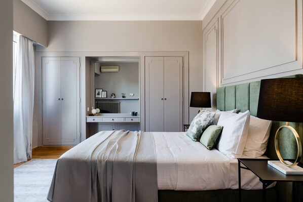 A bedroom with a large bed, a bedside table with a lamp, a dresser, and a mirror.