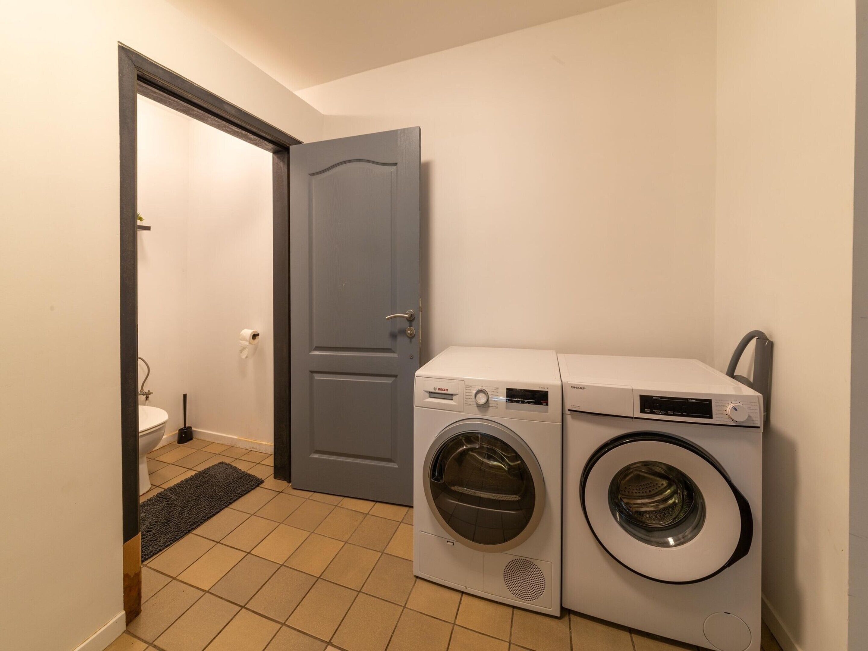 Ein Waschraum mit zwei Waschmaschinen und einer Toilette.