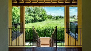 A covered outdoor area with a view of a grassy field and trees. - Belvilla by OYO Bilo del Ruscello (Manerba del Garda)