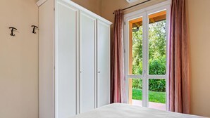 A bedroom with a large bed, a wardrobe, and a window with curtains. - Belvilla by OYO Bilo del Ruscello (Manerba del Garda)