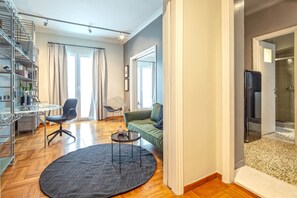 Ein modernes Wohnzimmer mit Glastisch, rundem Couchtisch, einem grünen Sofa und einer Duschkabine aus Glas.