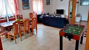 A living room with a dining area, a sofa, a television, and a foosball table. - Detached House at Country Side, Fenced Private Garden Ideal for 2 Fam, Wifi (Vodnjan)