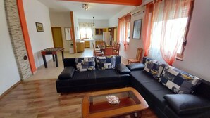 A living room with a black sofa, a wooden coffee table, and a dining area in the background. - Detached House at Country Side, Fenced Private Garden Ideal for 2 Fam, Wifi (Vodnjan)