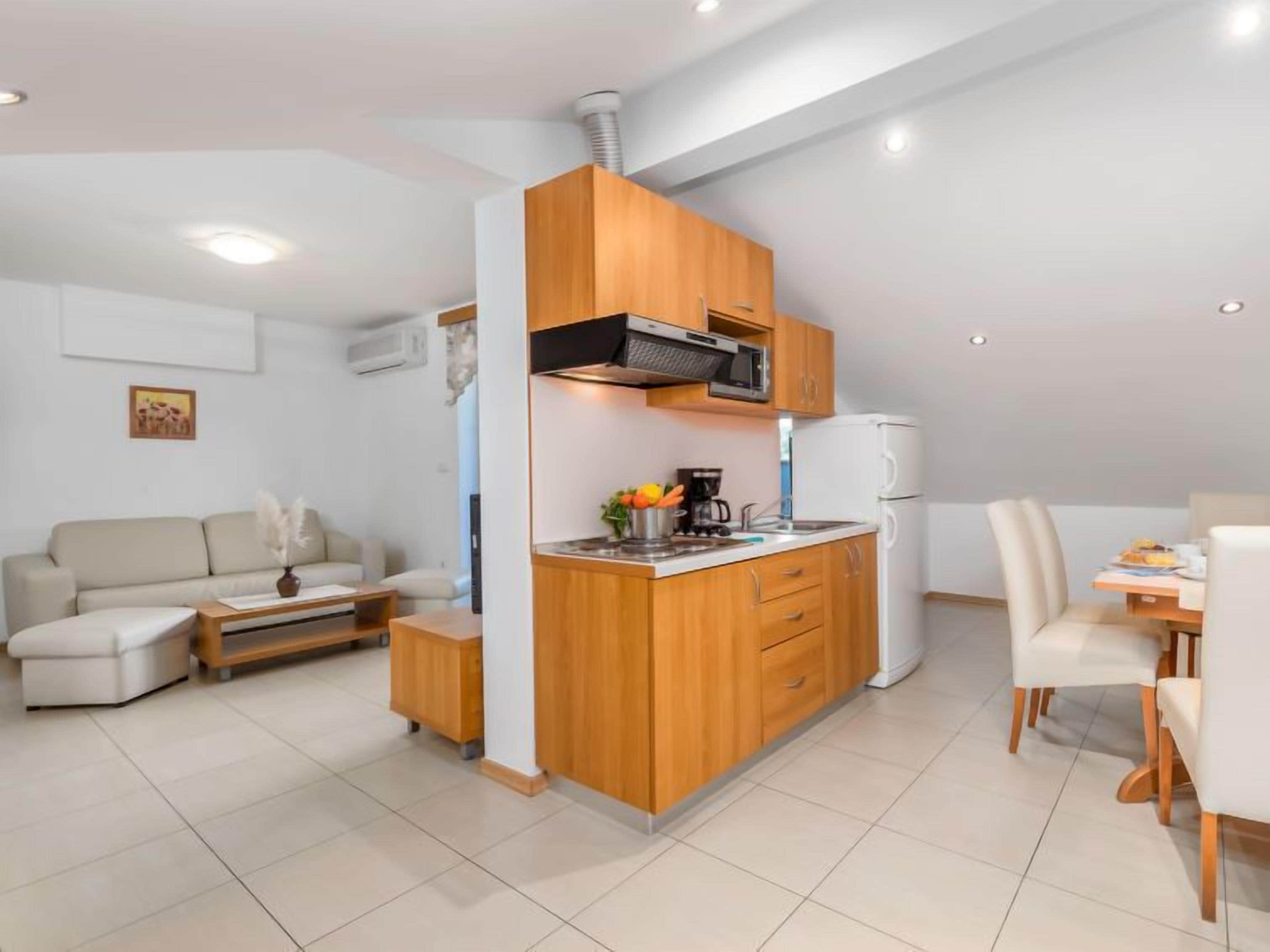 A compact living space with a kitchenette, a sofa, a dining area, and a small table.