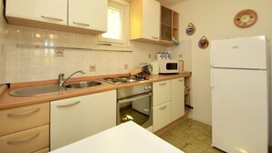 A compact kitchen with white cabinets, a sink, a microwave, and a refrigerator.