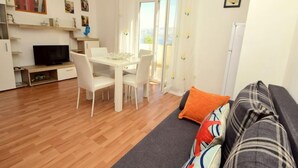 A compact living space with a dining area, a sofa, and a television. - Villa Bay View by Interhome (Brač/Postira)