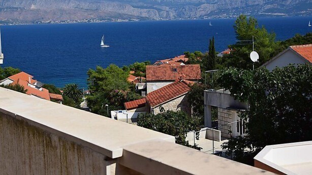 A coastal town with red-roofed buildings, a clear blue sea, and mountains in the background. - Villa Bay View by Interhome (Brač/Postira)