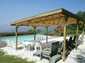 A covered outdoor area with a pool, lounge chairs, and a table. - Belvilla by OYO Casa Stella (Pescia)