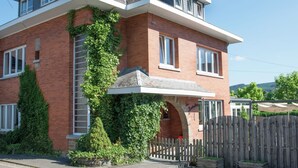 Ein zweistöckiges Haus mit Backsteinfassade, Holzzaun und kleinem Garten.