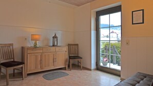 Ein Zimmer mit Holzboden, einem großen Fenster mit Blick auf eine verschneite Landschaft, einem Holzschrank, zwei Stühlen und einem kleinen Teppich.