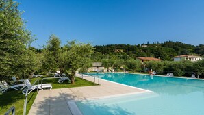 Ein Schwimmbecken mit Liegestühlen und freiem Blick auf die umliegende Landschaft.