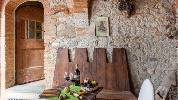 A rustic interior with a stone wall, wooden table, and a sign reading "ARCHI". - Belvilla by OYO Archi (Monteroni d'Arbia)