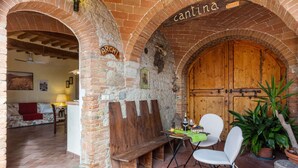 A rustic interior with brick arches, a wooden door labeled "cantina," and a seating area with a table and chairs. - Belvilla by OYO Archi (Monteroni d'Arbia)