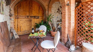 An outdoor dining area with a wooden table set for two, a chair, and a potted plant. - Belvilla by OYO Archi (Monteroni d'Arbia)