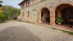 A stone building with arched doorways and a gravel driveway. - Belvilla by OYO Archi (Monteroni d'Arbia)