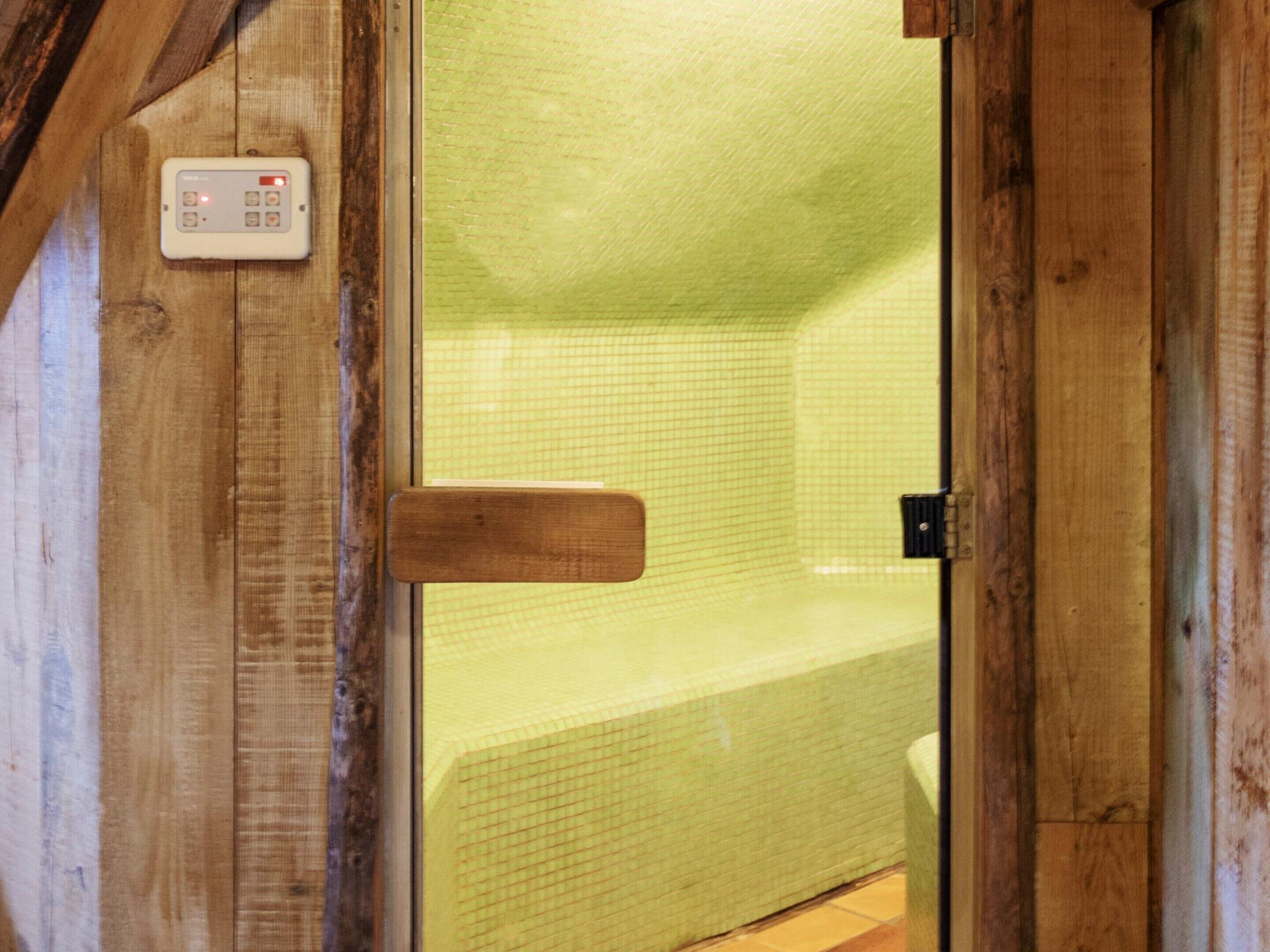 A wooden door with a control panel and a view into a room with a tiled wall.
