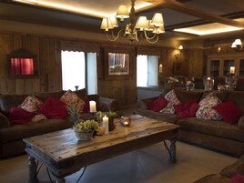 Una sala de estar acogedora con paredes y muebles de madera, una araña y una mesa con frutas y velas.