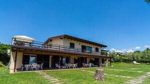 A two-story building with a covered patio area, outdoor seating, and a grassy lawn. - Apartment in Manerba Near Lake Garda (Manerba del Garda)