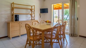 A dining area with a wooden table and chairs, a buffet counter, a coffee maker, and a television on the wall. - Apartment in Manerba Near Lake Garda (Manerba del Garda)