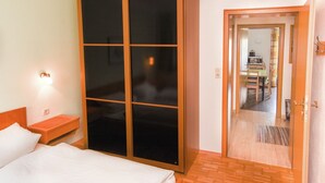 Ein Hotelzimmer mit großem Kleiderschrank, einem Bett mit weißer Bettwäsche, einem Nachttisch und einer Wandleuchte.