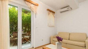 A modern living room with a sofa, a coffee table with a vase, and a sliding glass door leading to an outdoor area with a table and chairs. - Apartment Mare 3 by Interhome (Rab/Kampor)