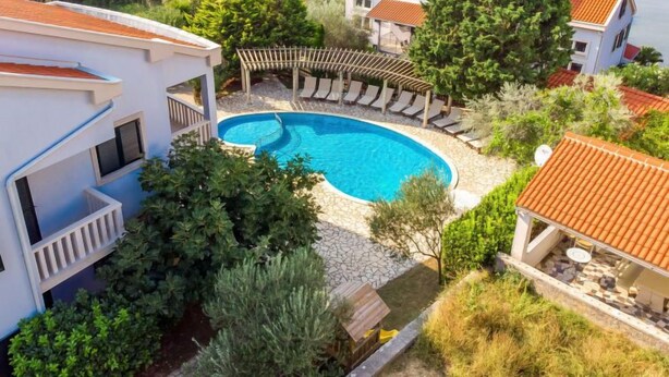 A resort with a swimming pool surrounded by lounge chairs, a pergola, and a view of the sea. - Tomislav 1 by Interhome (Rab/Kampor)